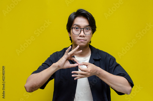 asian young students happily using sign language isolated against yellow background. asian man showing interpretation sign in deaf language.