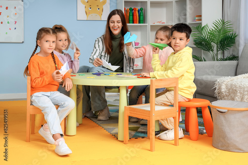 Little children with nursery teacher playing in kindergarten