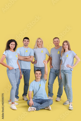 People with yellow awareness ribbons on color background. World Cancer Day