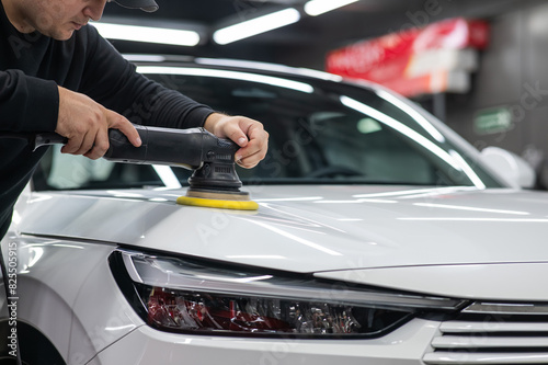 Process of polishing white car hood surface using orbital polishing machine. 