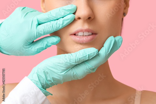 Surgeon hands touching woman nose before plastic surgery on pink background, closeup