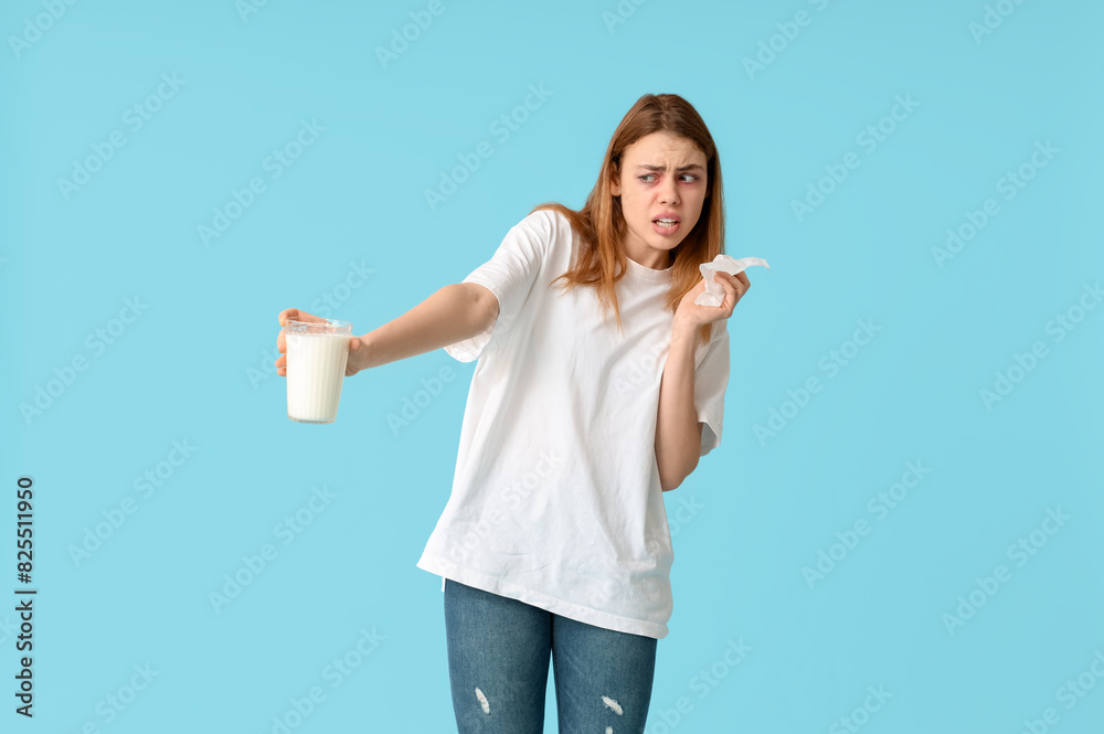 Young woman with glass of milk and tissue suffering from allergy on blue background Young woman with glass of milk and tissue suffering from allergy on blue background