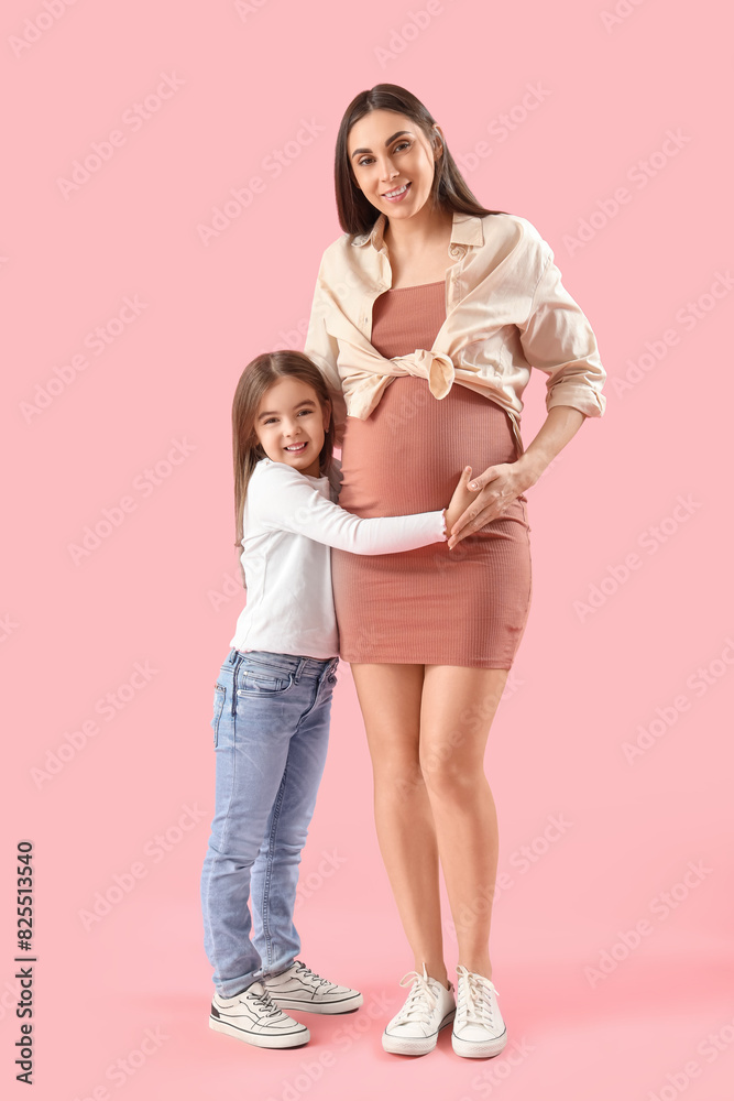 Little girl hugging her pregnant mother on pink background Little girl hugging her pregnant mother on pink background
