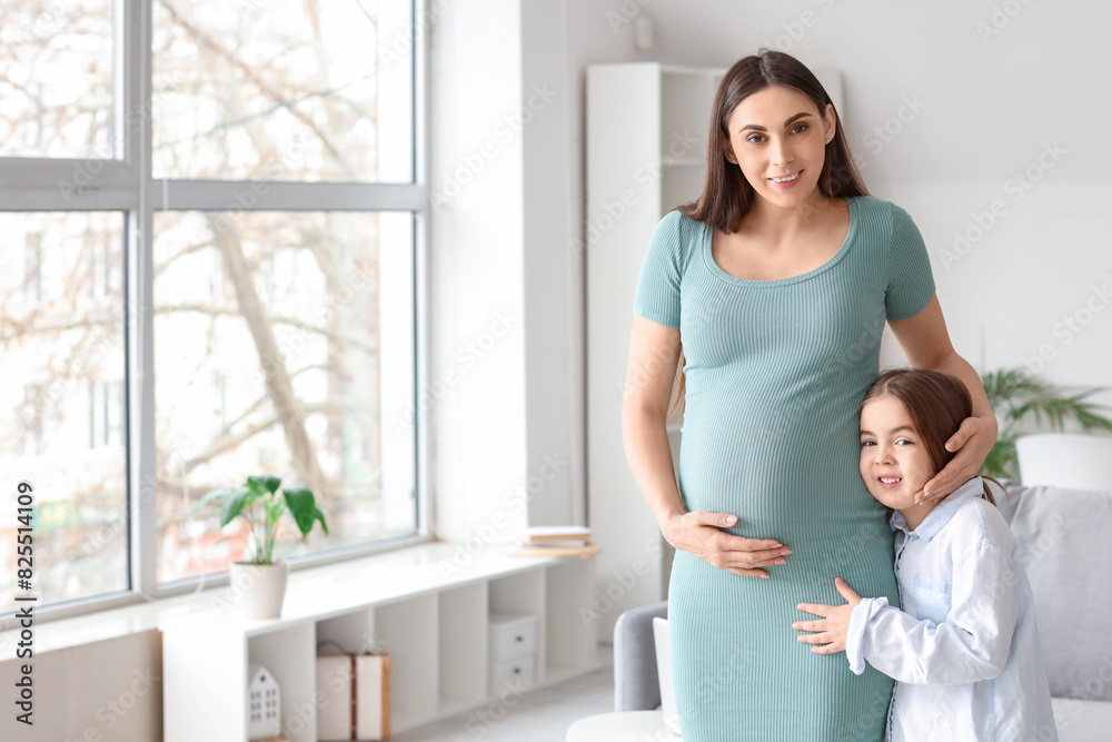 Little girl with her pregnant mother hugging at home