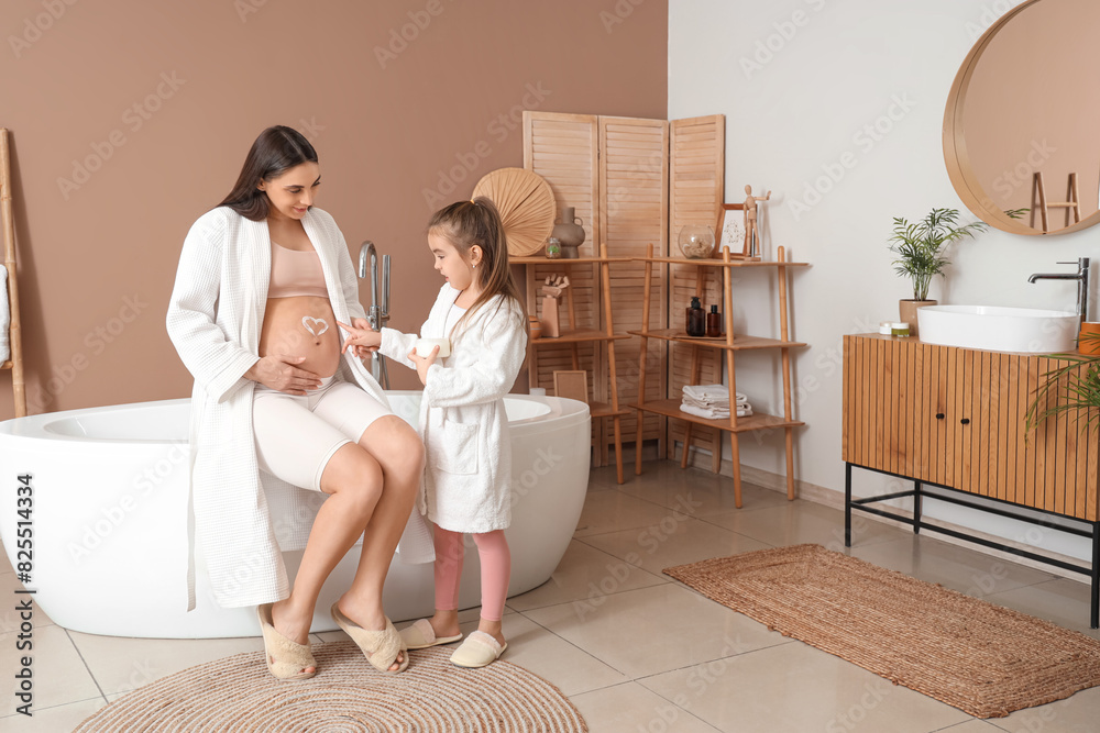 Little girl with her pregnant mother applying cream on belly in bathroom Little girl with her pregnant mother applying cream on belly in bathroom