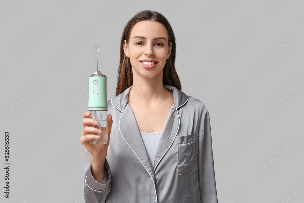 Beautiful young woman with oral irrigator on grey background Beautiful young woman with oral irrigator on grey background