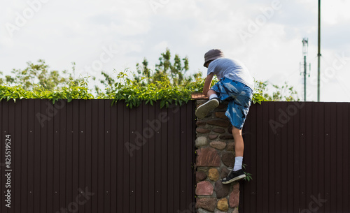 A little boy climbs over a fence on a private plot