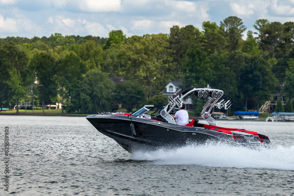 Fototapeta premium Boater on gray wakeboard wake boat enjoying summer day on freshwater lake.
