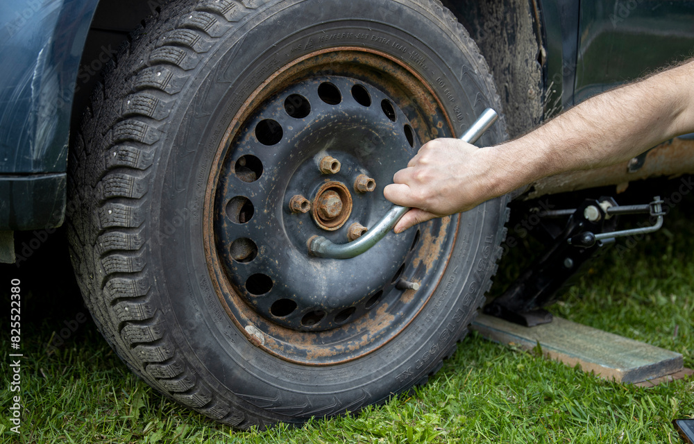 A man diligently works on a tire, situated on a bed of lush green grass, surrounded by natures tranquility. A man diligently works on a tire, situated on a bed of lush green grass, surrounded by natures tranquility.