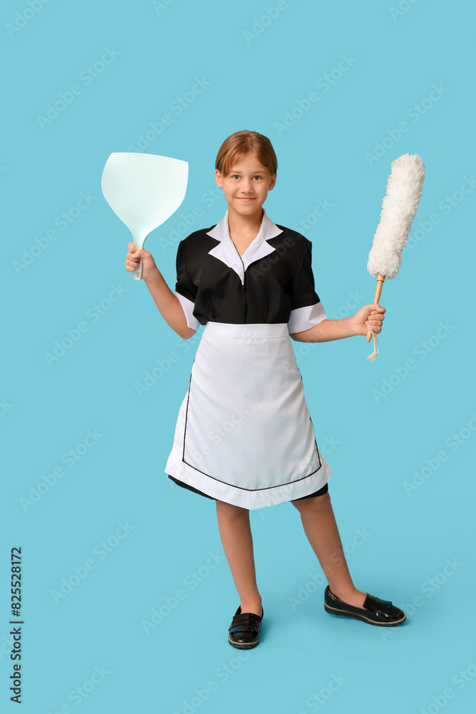 Portrait of teenage chambermaid with pp-duster and dustpan on blue background Portrait of teenage chambermaid with pp-duster and dustpan on blue background
