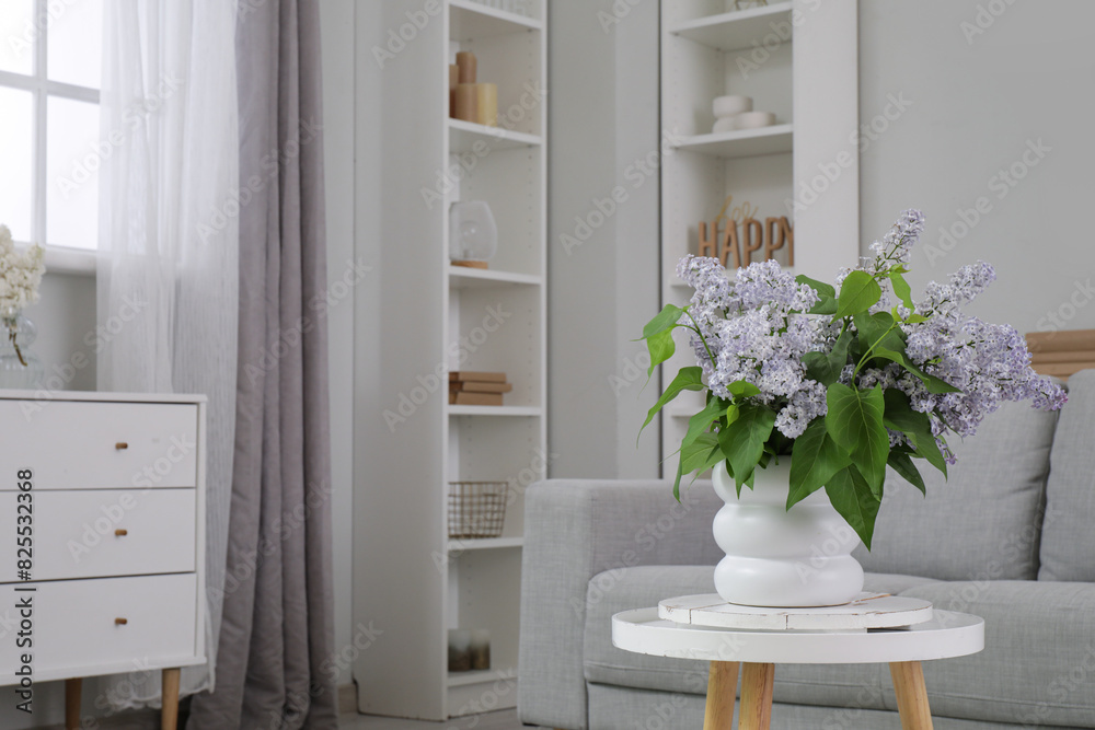Sofa, decor on shelves, table with flowers in vase and chest of drawers in interior of living room Sofa, decor on shelves, table with flowers in vase and chest of drawers in interior of living room