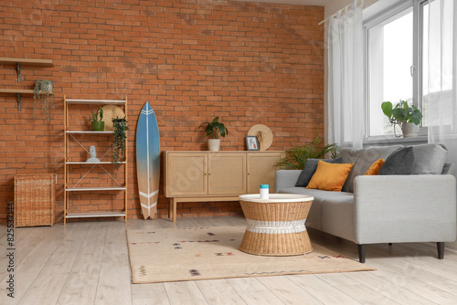 Surfboard, grey sofa and chest of drawers in beautiful living room