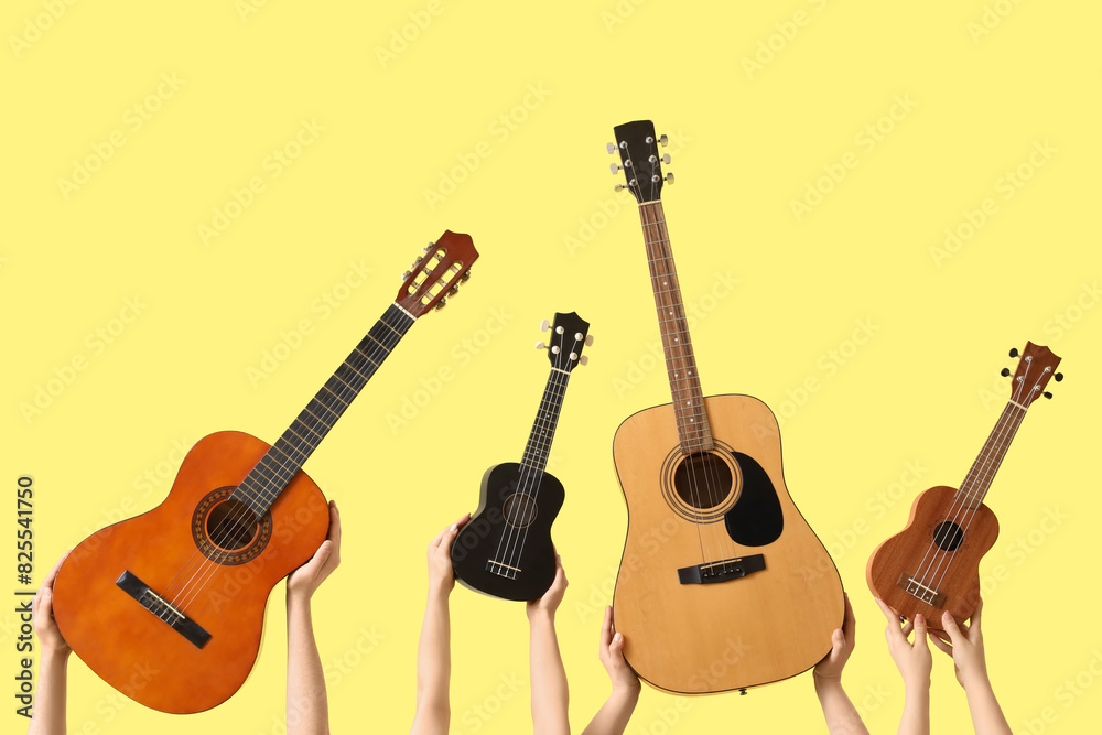 Fototapeta premium Women with guitars on yellow background