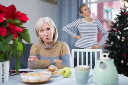 Portrait of a mature woman resentful of her adult daughter, sitting at a table