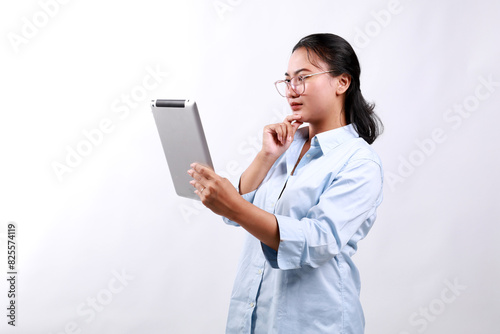 Portrait of asian business woman looking at digital tablet with thinking gesture, side view. Isolated on white