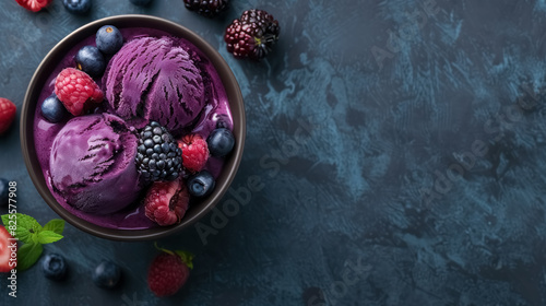top view of acai bowl with ice cream and mixed berries on dark background photo