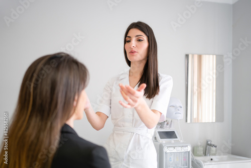Foto Young female cosmetician preparing client for facelift injection