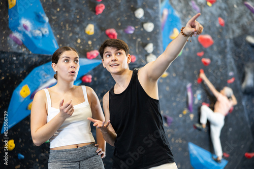 Young guy and girl getting ready to climb wall in gym