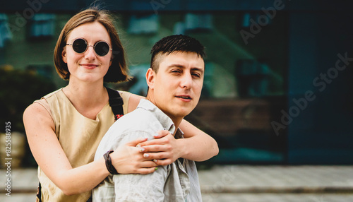 Two people walk in a city, a man and a young woman hugging and having fun together.