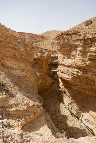 Picturesque view of sunlit Tamaghza canyon with imposing sandstone cliffs standing as timeless monuments to sculpting forces of nature in Tunisia