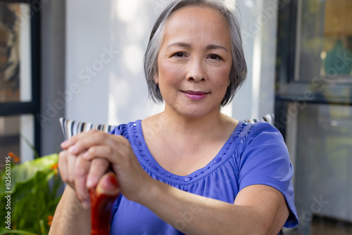 Outdoors, Asian middle-aged female in blue top, holding a cane