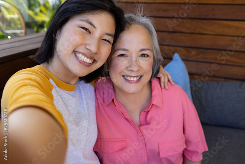 At home, Asian middle-aged mother and young adult daughter smiling for selfie