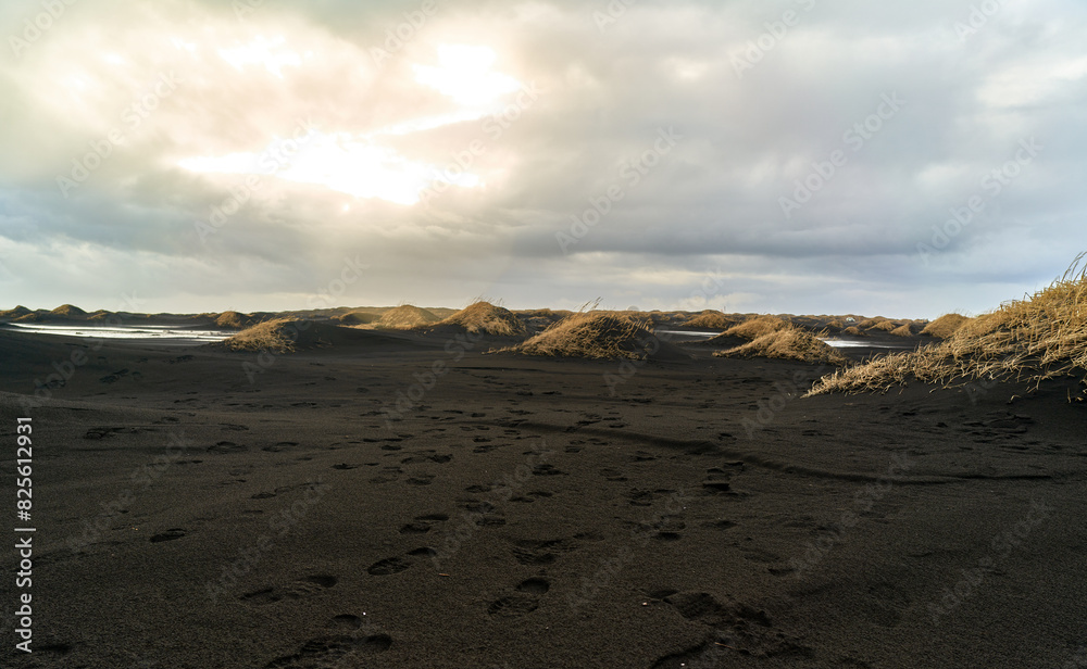 Footprints in the sand of the black Vestrahorn beach with sun rays between the clouds Footprints in the sand of the black Vestrahorn beach with sun rays between the clouds