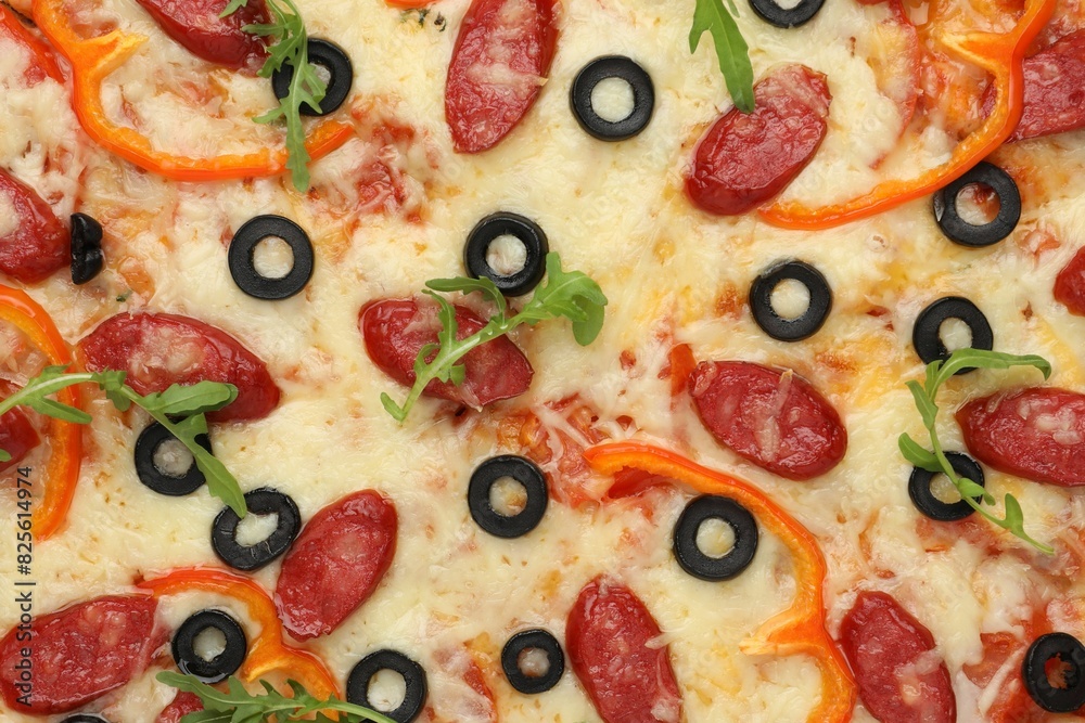 Tasty pizza with cheese, dry smoked sausages, olives, pepper and arugula as background, top view Tasty pizza with cheese, dry smoked sausages, olives, pepper and arugula as background, top view