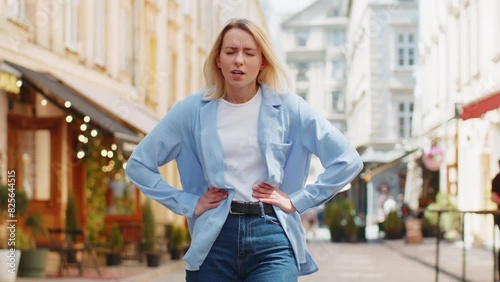 Caucasian young woman traveler feeling sudden strong abdominal stomach ache gastritis problem. Upset tourist lady having symptom poisoning diarrhea indigestion peptic ulcer pancreatitis on city street