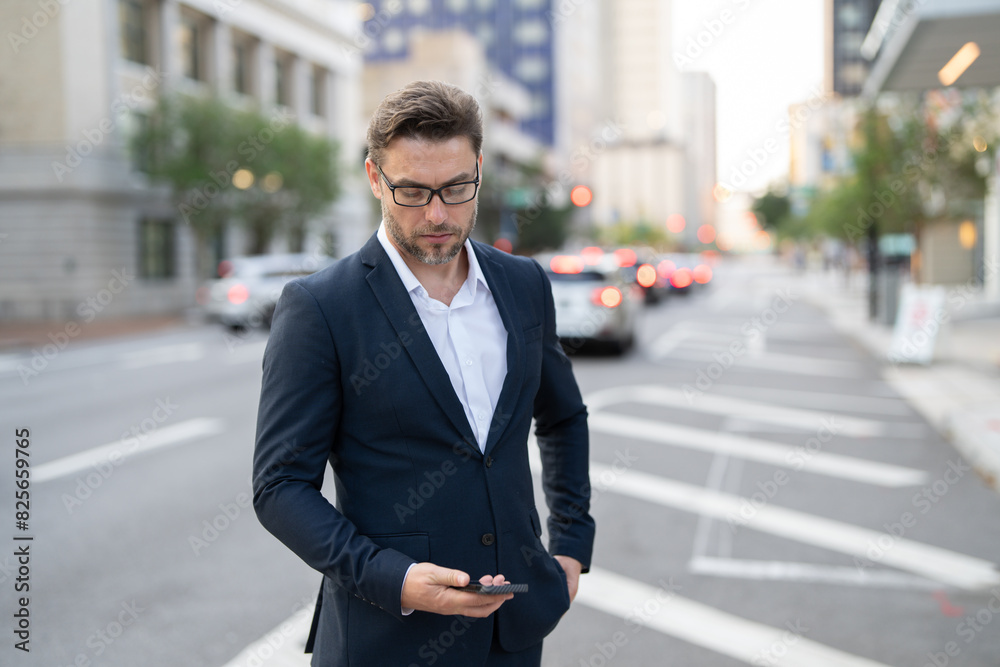 A handsome young businessman using his phone and standing on the street. Handsome smiling young businessman smartly dressed standing outdoors at the city street, using mobile phone A handsome young businessman using his phone and standing on the street. Handsome smiling young businessman smartly dressed standing outdoors at the city street, using mobile phone