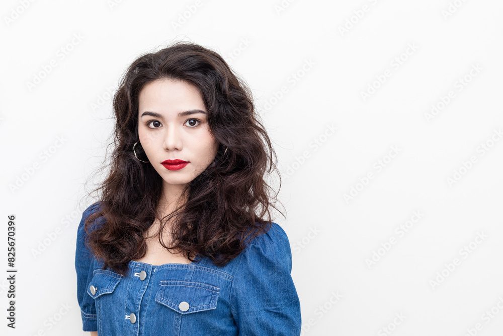 A beautiful woman with curly hair in a denim skirt on a solid background