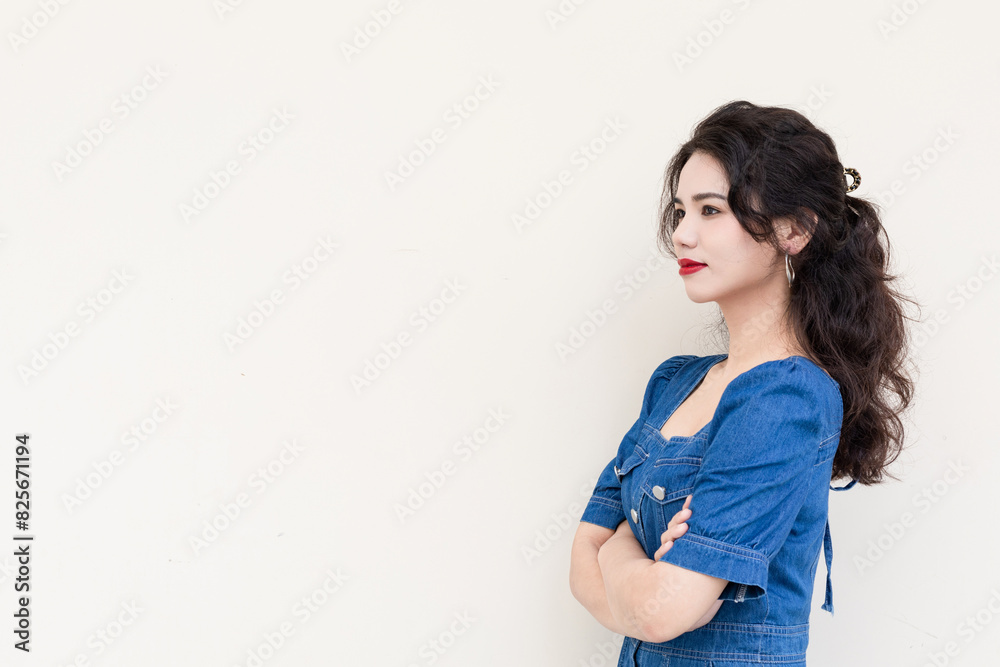A beautiful woman with curly hair in a denim skirt on a solid background A beautiful woman with curly hair in a denim skirt on a solid background