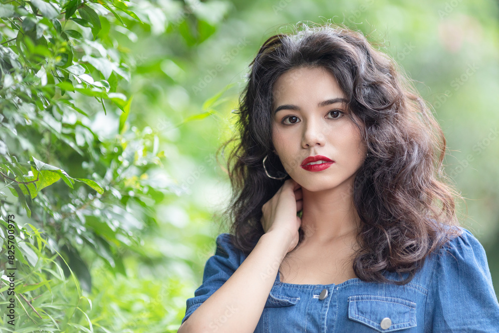 Outdoors a curly-haired Chinese beauty in a denim skirt