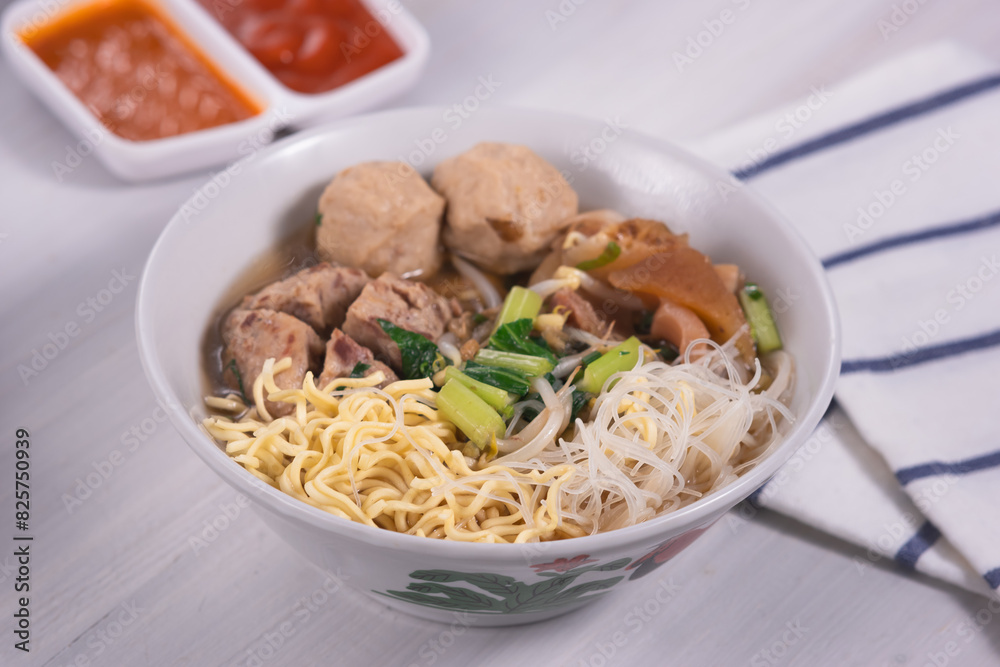 Meatballs or Bakso, one of Indonesian specialties. Served with yellow noodles, vermicelli and vegetables in a white bowl Meatballs or Bakso, one of Indonesian specialties. Served with yellow noodles, vermicelli and vegetables in a white bowl