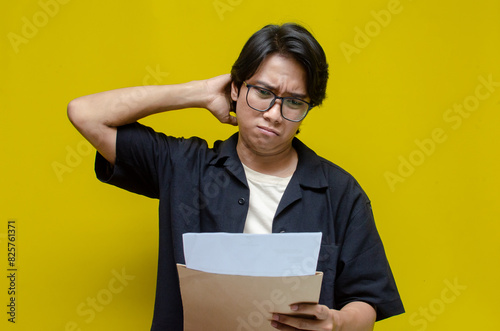 asian man opening envelope receiving and reading bad news letter. An angry man is upset over his excessive expenses, notice of termination, bank debt, and tax invoice.