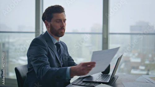 Busy accountant working laptop sitting office looking documents at desk closeup