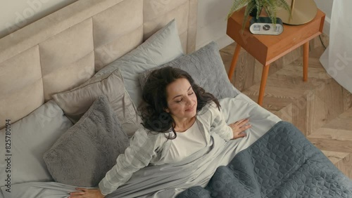 Top view brunette woman wake up checking time in smartphone mobile phone late rush for work university get out of bed quickly fast speedy oversleep home inside bedroom sleeping female lying lateness