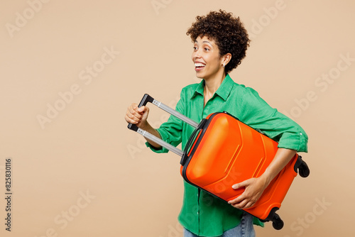 Traveler woman wear green casual clothes hold passport ticket bag look aside isolated on plain beige background. Tourist travel abroad in free spare time rest getaway. Air flight trip journey concept.