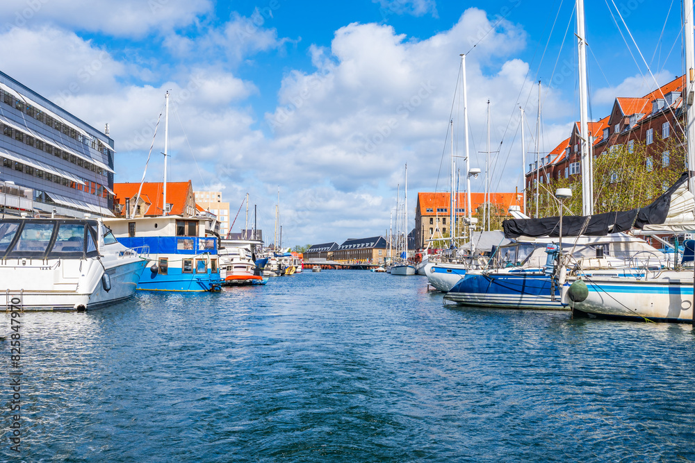 View of water front in Christianshavn district of Copenhagen with boats and yachts moored along a canal embankment. Denmark