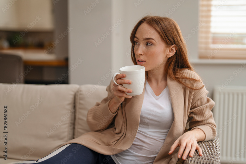 relaxed redhead woman drinking coffee tea sitting on sofa at home relaxed redhead woman drinking coffee tea sitting on sofa at home