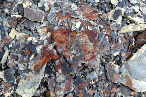 Photo of stone texture. Macro. Various shades of brown, orange, red, gray and white. Stones of different sizes. They have black cracks and crevices. Chaotic placement. photo