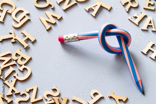 Quadro su tela Pencil with knot and scattered letters, dyslexia concept