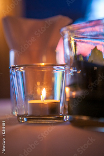 A candle in a glass holder creates a cozy and warm ambiance in a softly lit room, perfect for relaxation