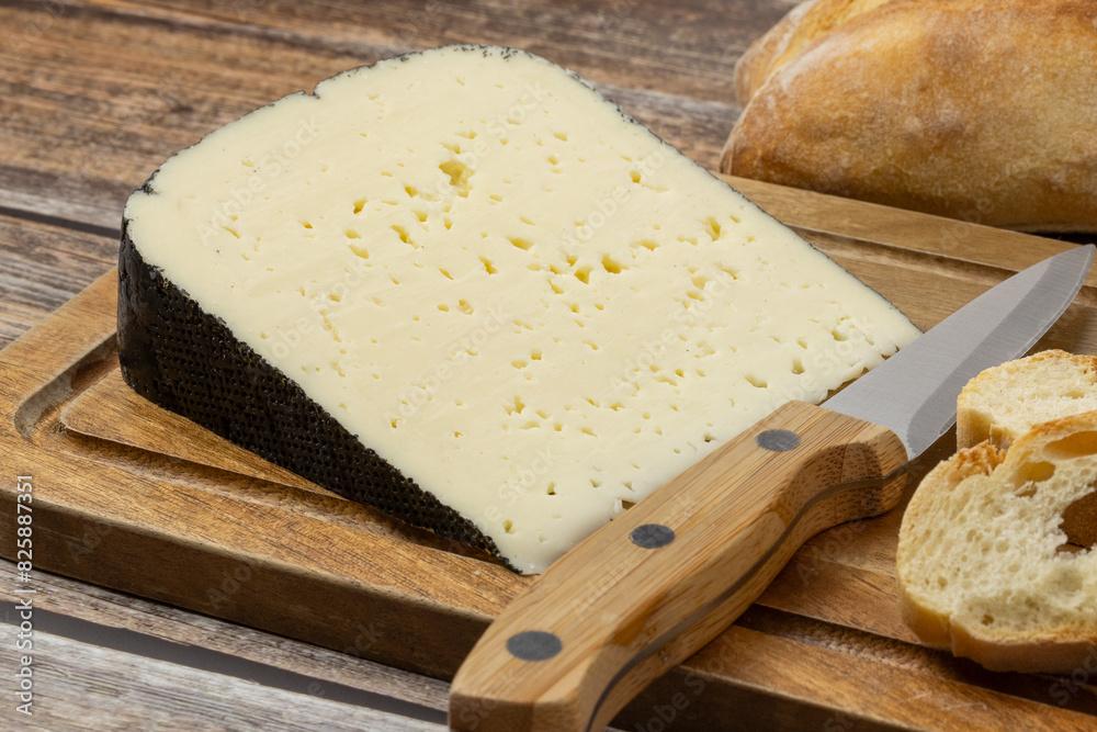 tranche de fromage : tomme noire des Pyrénées, en gros plan, sur une table tranche de fromage : tomme noire des Pyrénées, en gros plan, sur une table