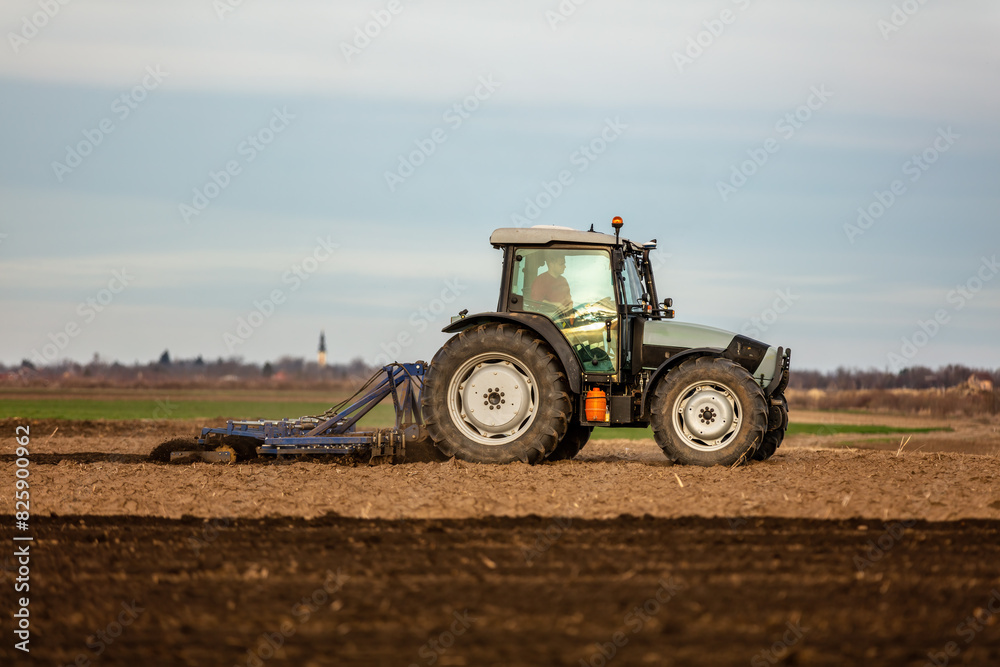 Tractor with a plow attachment tilling the soil in a vast farmland setting Tractor with a plow attachment tilling the soil in a vast farmland setting