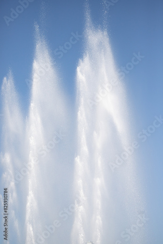 The fountain splashes in the blue sky. Water in flight.