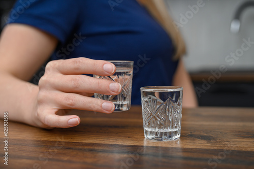 Pić alkohol, kieliszek do wódki w dłoni kobiety 