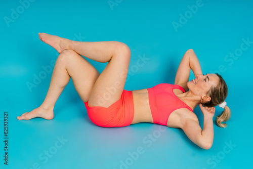 Full length portrait of smiling young woman in sportswear isolated over studio background.
