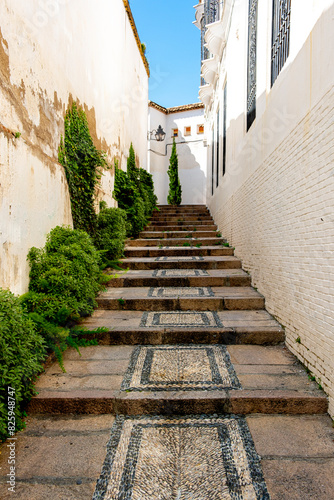 Upwards perspective of a narrow alley with steps and white walls in Cordoba, Andalusia, Spain, a typical sight in spring photo