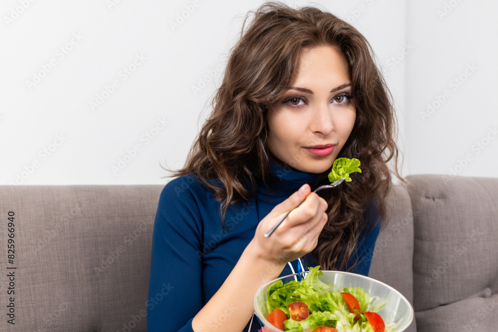 girl with salad. a young slender girl in a blue jacket sits on the sofa and eats a salad with a fork, close-up concept useful girl with salad. a young slender girl in a blue jacket sits on the sofa and eats a salad with a fork, close-up concept useful